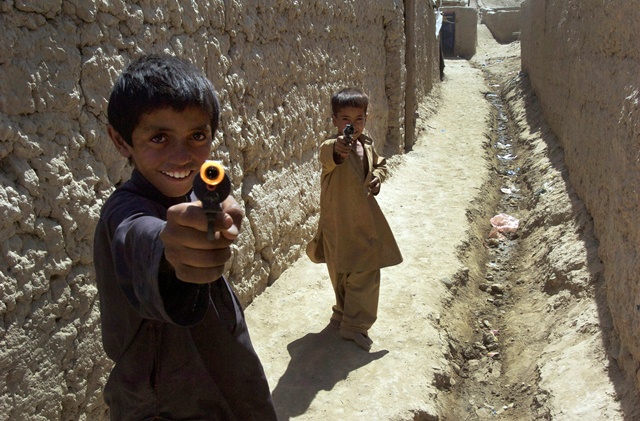 Afghan boys playing with toy guns run into a village alley in Bagram, Afghanistan. Photo: Eric Kanalstein / UNAMA