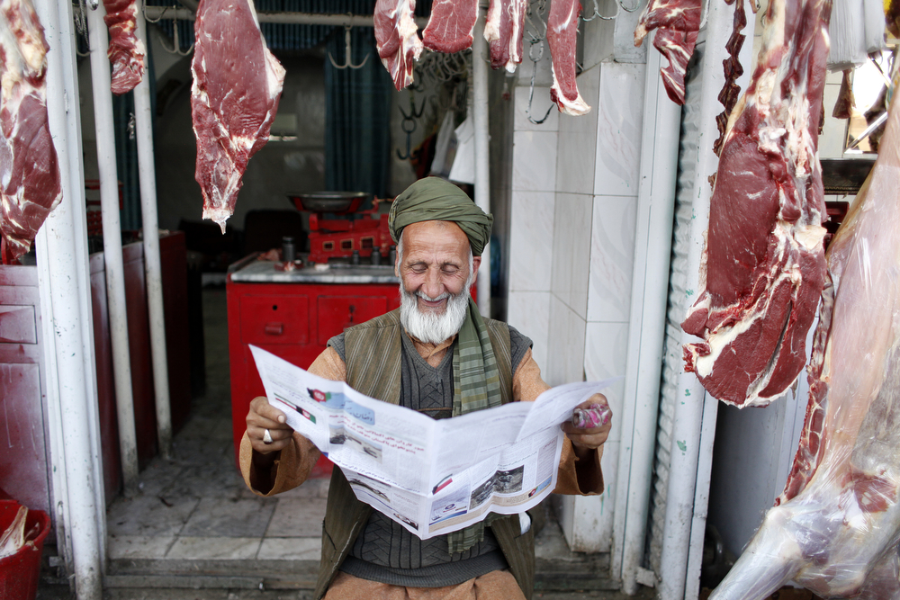 A meat seller in Kabul reading newspaper. Photo: Fardin Waezi / UNAMA